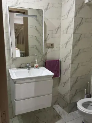 a white bathroom with a sink and a mirror at Appartement abwab tamaris in Dar Mouddene