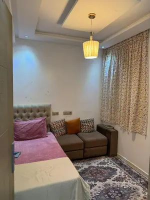a bedroom with a bed and a couch and a window at Appartement abwab tamaris in Dar Mouddene