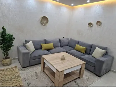 a living room with a blue couch and a coffee table at Appartement bien meublé in Rabat