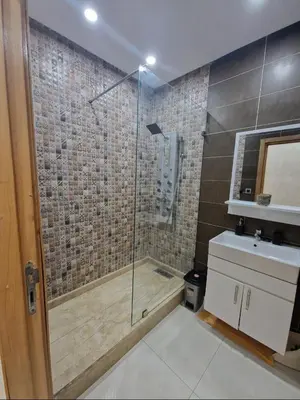 a bathroom with a glass shower and a sink at Appartement bien meublé in Rabat