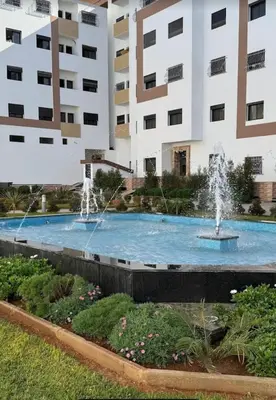 a fountain in front of a large building at appartement meublé temara in Temara