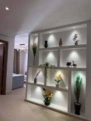 a living room with white shelves with flowers on them at N22 Élégance et Confort à La Corniche Rabat - Appartement de Luxe Essabah in Rabat
