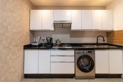 a kitchen with white cabinets and a washing machine at Family apartment Terrace Pool Wi-Fi in O Ben Slimane