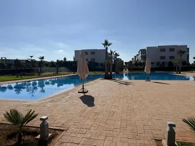 a swimming pool with two umbrellas next to a building at Blue Beach in Casablanca