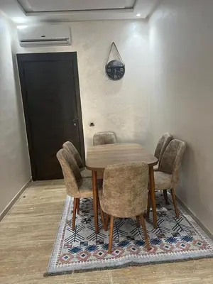 a dining room table and chairs in a room at Elegance Pool View Apartment in Dar Bouazza