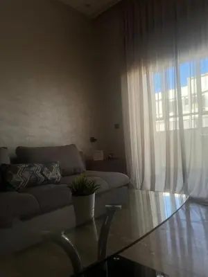 a living room with a couch and a glass table at Elegance Pool View Apartment in Dar Bouazza