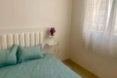 a bedroom with a bed with a lamp and a window at Appartement Moderne et Équipé Proche Aéroport CMN in Nouaseur