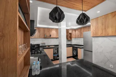 a kitchen with black counter tops and wooden cabinets at Harhoura Luxury Stay, Steps from the Beach in Temara