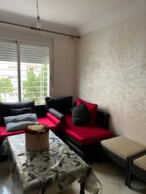 a living room with a red couch and a table at Appartement serein & apaisant in Bouznika