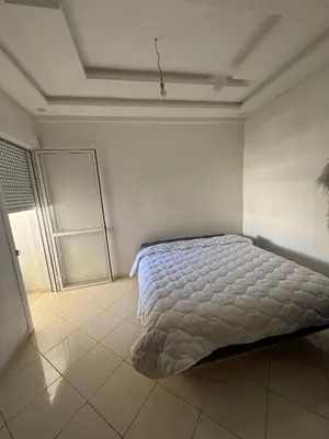 a bedroom with a bed in a white room at chambre saada in Dar Bouazza