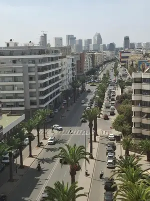 a city street with cars and palm trees and buildings at Luxurious and cozy CFC panoramic view studio in Casablanca
