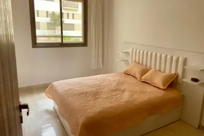 a white bedroom with a bed with a window at Appartement Moderne Équipé Proche Aéroport Mohammed V in Nouaseur