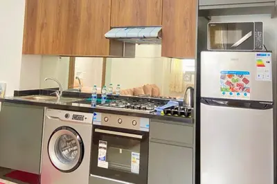 a kitchen with a stove and a refrigerator at Appartement Moderne Équipé Proche Aéroport Mohammed V in Nouaseur