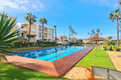 a swimming pool in a resort with palm trees at Beachside Charming Apartment in Tamaris