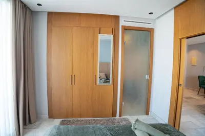 a bedroom with a wooden closet and a mirror at Cedar Stays Studio apartment 1chambre salon - WiFi - climatisation - parking - machine a laver- 5 min CFC in Casablanca