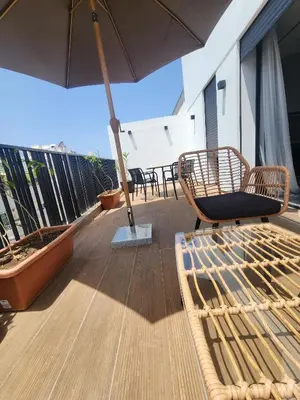 a balcony with an umbrella and chairs and tables at The 28 Triangle d'Or by IB Signature - Stylish two-Bedroom flat - Wifi, Self Check-in, Day and Night Security, Terrace, Swimming pool, free parking close to all amenities in Casablanca