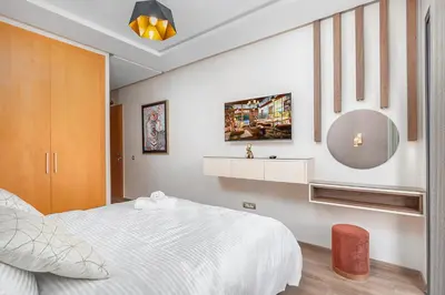 a bedroom with a white bed and a mirror at Luxury Apartment Perles d'Agdal, Facing Agdal Station in Rabat