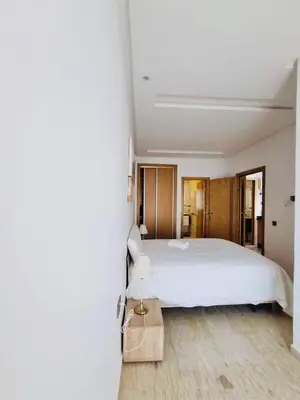 a bedroom with a white bed and a wooden floor at BenHost Appartement Casablanca Maarif in Casablanca