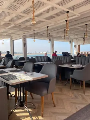 a dining room with tables and chairs and windows at Luxury Beach Front Cherrat Plage Apartment in Sidi el Haj Bou Derbala