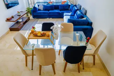 a living room with a table and chairs and a blue couch at VIVASTAY Casablanca - Urban Nest 3 Bedrooms High Standing Les Princesses in Casablanca