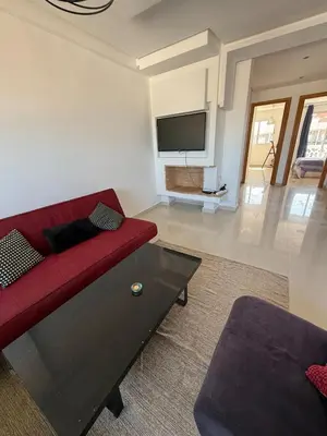 a living room with a red couch and a flat screen tv at Cozy Dream Land Appartement 1 bed room Sea View, Sidi Rahal Beach in Sidi Rahal