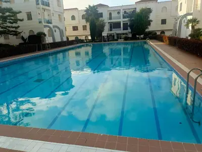 a swimming pool in a hotel with blue water at appartement à al tilal in Mohammedia