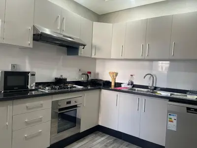 a kitchen with white cabinets and black counter tops at Apartment in Manesman beach in Mohammedia