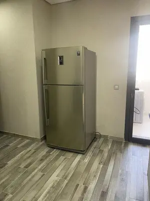 a stainless steel refrigerator in a room with a wooden floor at Apartment in Manesman beach in Mohammedia