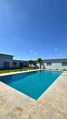 a blue swimming pool in front of a building at Ferme moderne avec piscine et jardin Sejour paisible au cœur de la nature in Berrechid