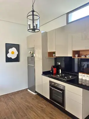 a kitchen with white cabinets and a black counter top at Ferme moderne avec piscine et jardin Sejour paisible au cœur de la nature in Berrechid