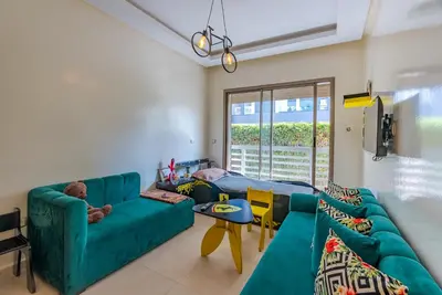 a living room with a green couch and a table at Spacious luxury apartment with pool in Bouznika