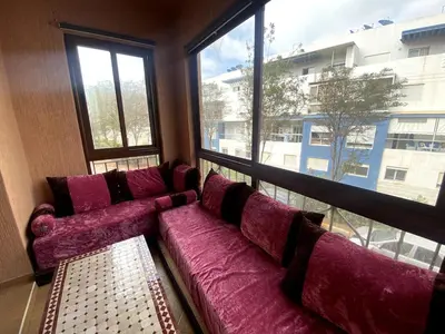 a large purple couch in a room with a large window at appartement a louer el mansouria in Pont Blondin