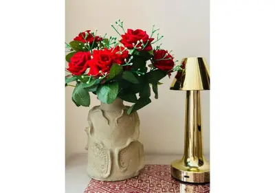 a vase with red roses in it next to a lamp at Walkable, Beach in 2, Terrace, DW, AC, PS4, WiFi in Mohammedia