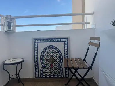 a bench and stool in a room with a rug at Blue Ocean Escape Sidi Rhal in Sidi Rahal