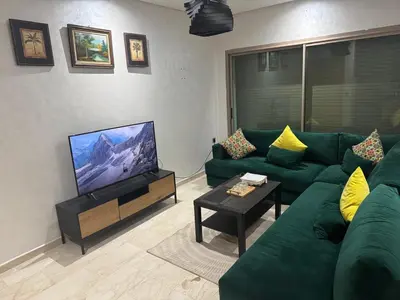 a living room with a green couch and a flat screen tv at Cosy Studio meublé in Casablanca