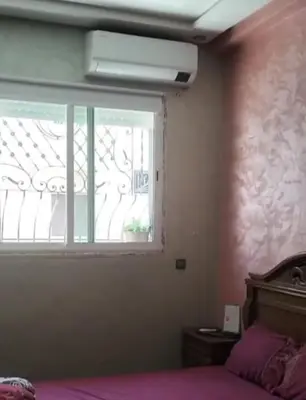 a bedroom with a window and a bed with purple sheets at Appartement Jad in Deroua