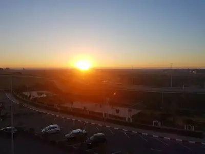 a sunset over a parking lot with cars parked at Best appartement pools view at Mansouria in Pont Blondin