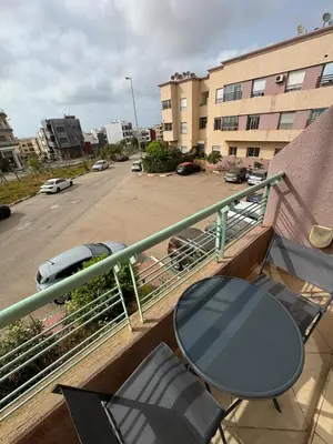 a table and chairs on a balcony with a parking lot at Apartement en Wifak Soleil, calme et sécurité in Temara