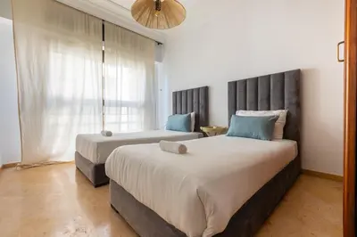 a bedroom with two beds and a large window at 3BR Apartment in Prestigious Hay Riad by MERAT HOME in Rabat