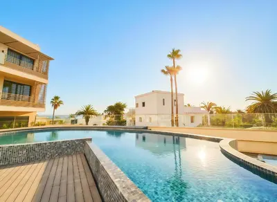 a swimming pool with palm trees and a building at Maya Suites - Opale Sea Side in Anfa-Supérieur