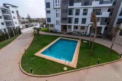 a swimming pool in the middle of a grassy area in a building at 3BR 3BA Family Apt Pool Gated Residence in Casablanca