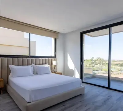 a bedroom with a white bed and large windows at Villa Prestige in Bir Jedíd Saint-Hubert