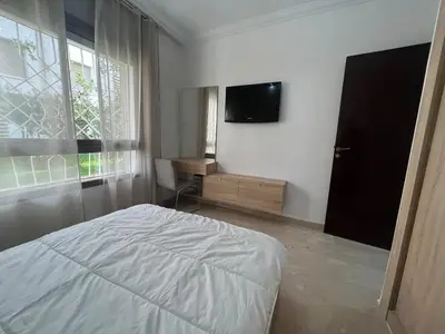 a bedroom with a bed and a tv on the wall at Modern appt with pool and easy access to beach in Skhirat