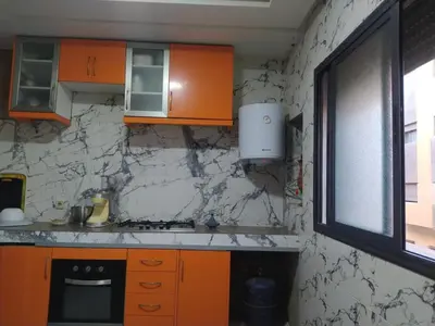 a kitchen with orange cabinets and marble walls at New Luxury Apart Victoria- Casablanca 2BR