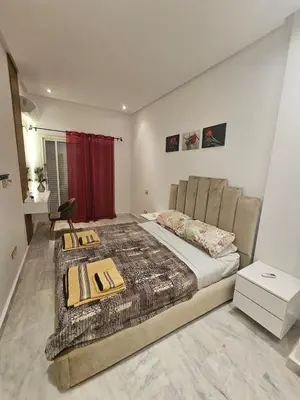 a bedroom with a large bed and a red curtain at Sables d'or flat apartement in El Harhoura