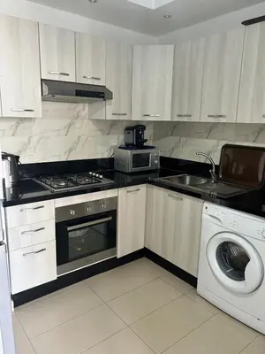 a kitchen with a stove and a washing machine at Beautiful Family Apartment Beach Paradise Residence in Pont Blondin