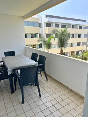 a balcony with a table and chairs and a building at Beautiful Family Apartment Beach Paradise Residence in Pont Blondin