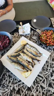a plate of fish on a table with bowls of food at Joumaira beach in Temara