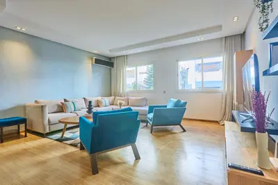 a living room with a couch and blue chairs at Gauthier Pearl - Luxury 3BR Apartment in Casablanca