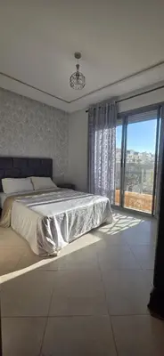 a bedroom with a bed and a large window at appartement a louer sable d'or mansouria in Pont Blondin